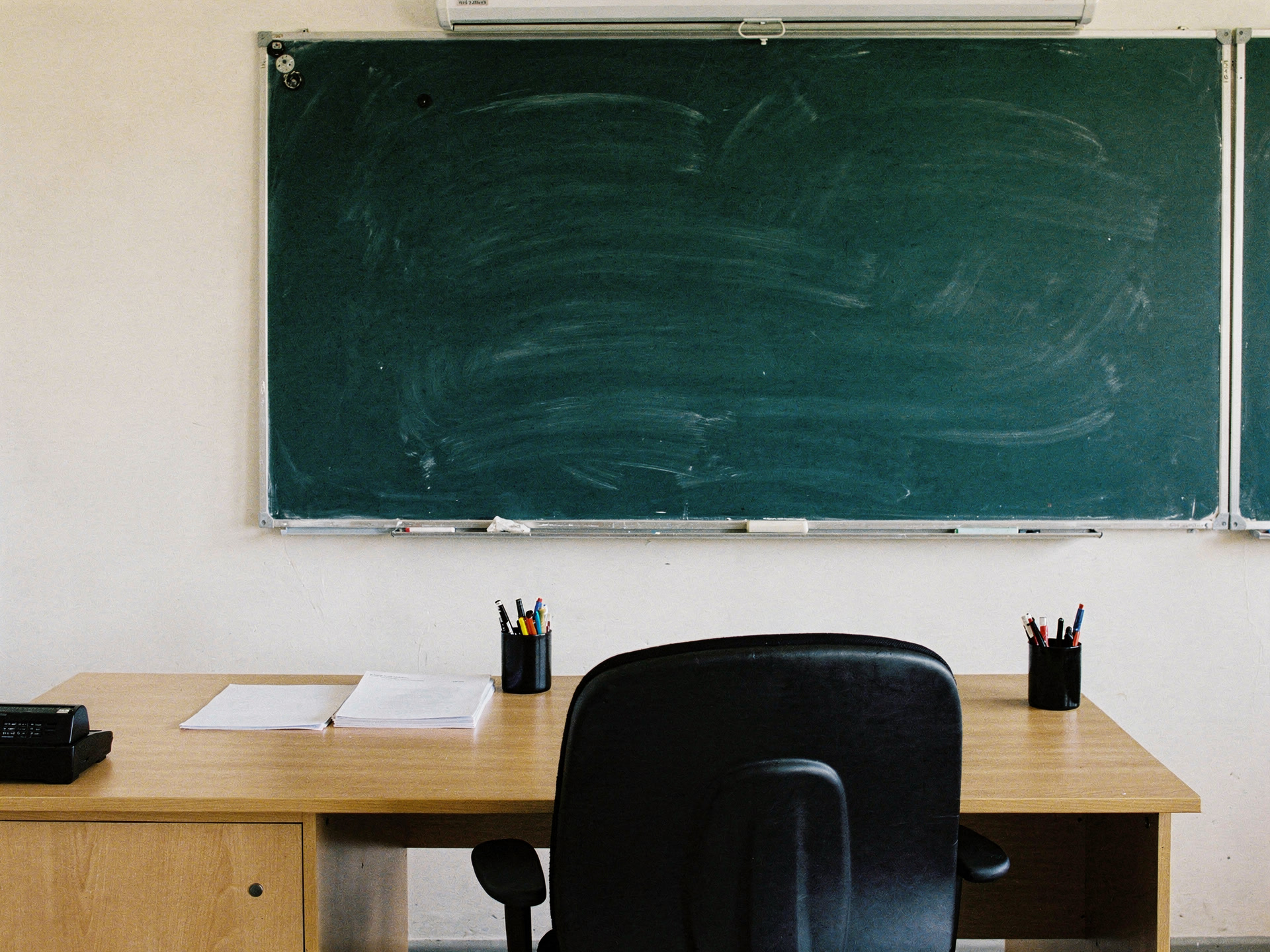 Empty teacher desk and chair in front of a smudged chalkboard