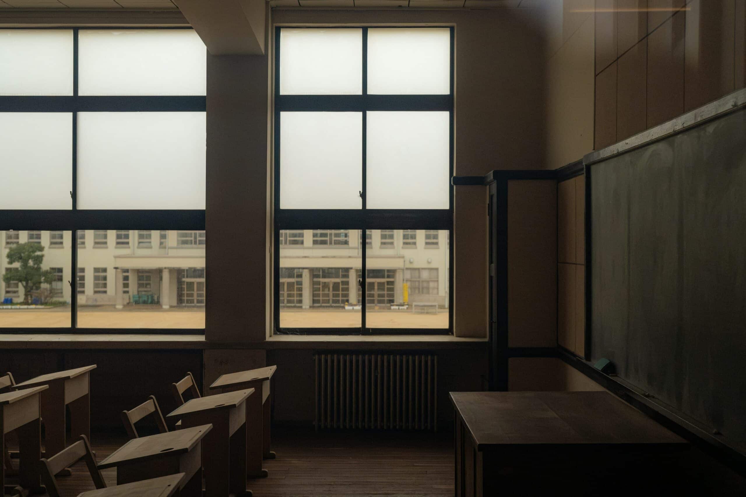 Empty classroom with desks and chalkboard, no people