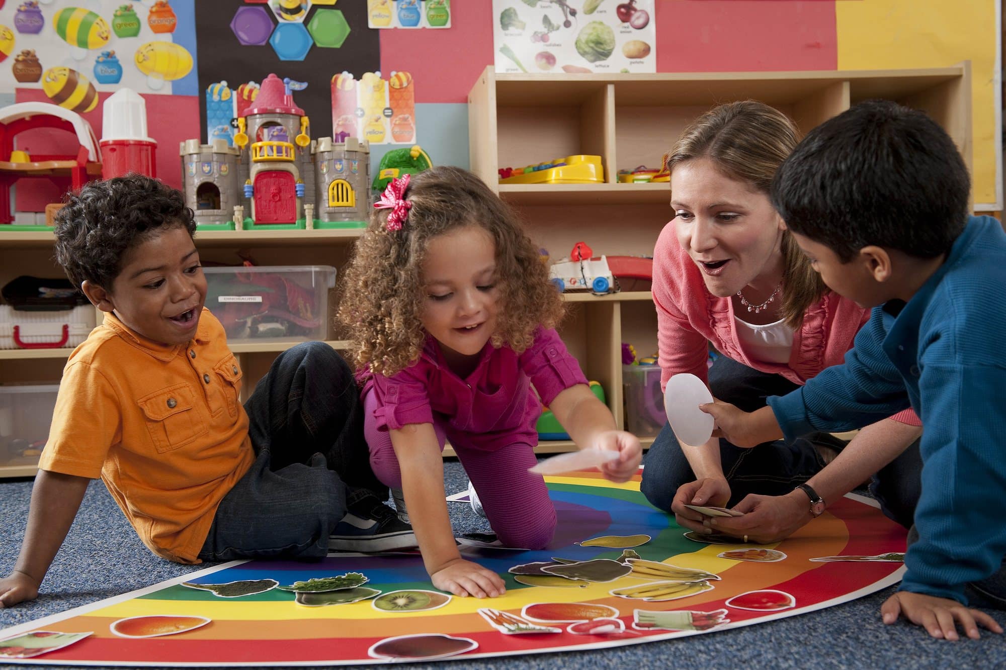 Young children sitting on a colorful classroom rug sorting picture cards together during a hands-on learning activity